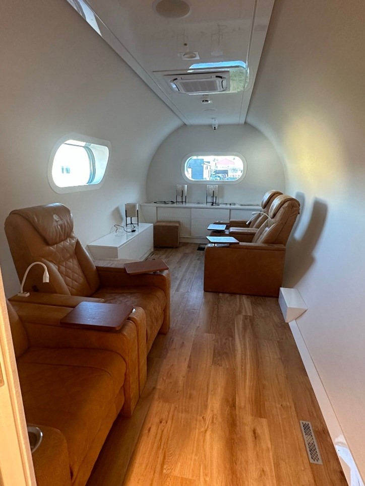 Luxurious interior of a normobaric oxygen chamber with leather recliners, wood flooring, and modern lighting.