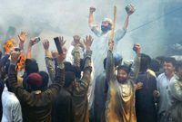 Group of islamic men in traditional clothing raising their arms and cheering, with smoke and fire in the background.