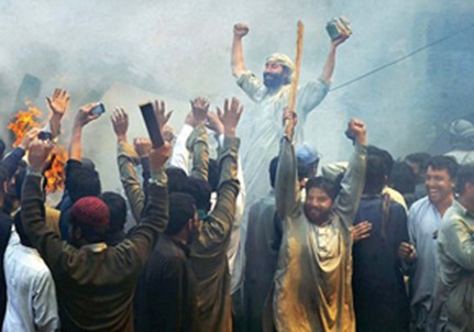 Group of islamic men in traditional clothing raising their arms and cheering, with smoke and fire in the background.