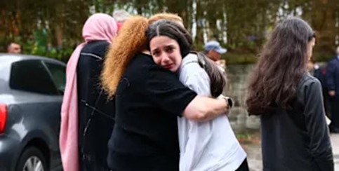 Photograph of emotional women embracing outdoors, conveying grief, support, and solidarity.