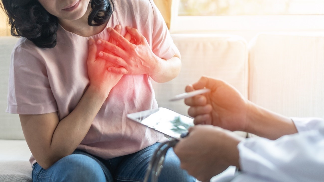 Woman experiencing chest pain while a healthcare professional prepares a syringe, illustrating potential heart-related complications following medical injections.