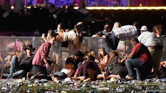 People crouching and seeking cover at an outdoor event amid apparent chaos.