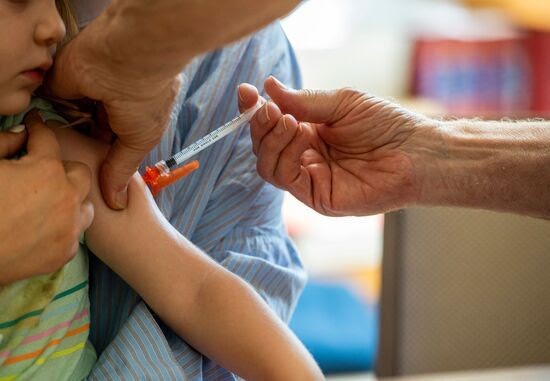 Child receiving a vaccine injection in the arm, representing immunization and discussions around vaccine-related health effects.