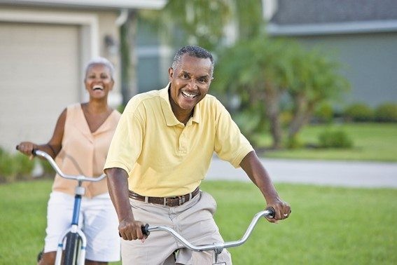 Active older couple riding bicycles outdoors in a residential neighborhood.