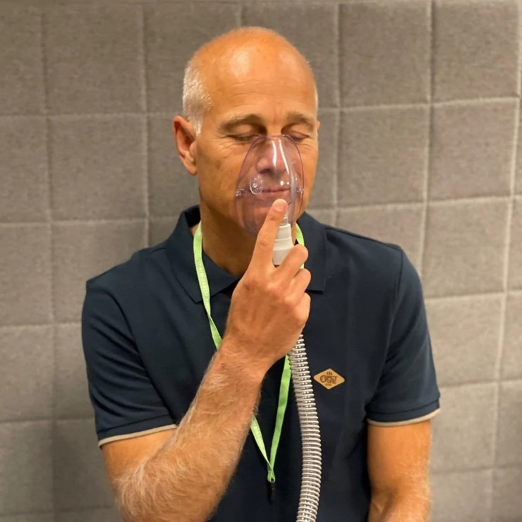 Person using a respiratory mask for carbogen inhalation therapy.