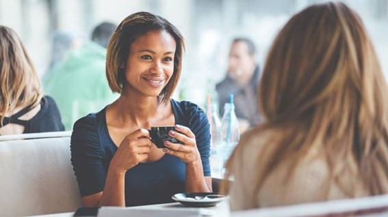 Two people having a conversation over coffee in a café.